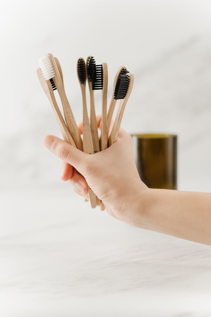 services-02 Close-up of a hand holding eco-friendly bamboo toothbrushes, promoting sustainability.